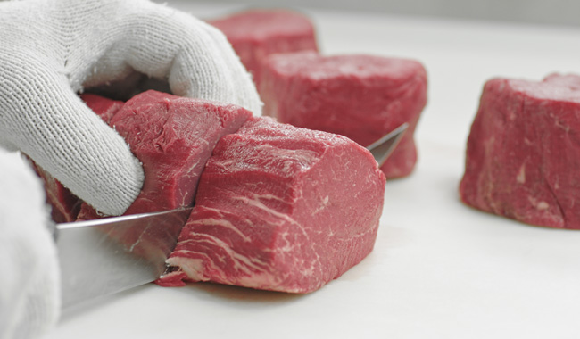 Butcher cutting beef tenderloin with filet knife